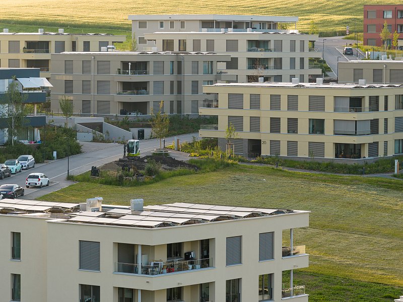 Mehrfamilienhäuser mit Balkonen und gemeinschaftlichen Aussenflächen aus erhöhter Perspektive.