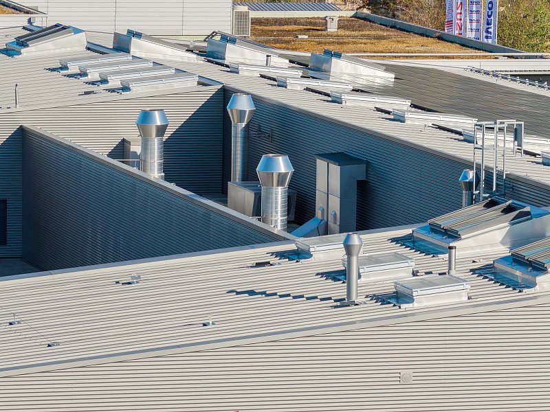 Metallene Dachflächen mit Lüftungsaufbauten und geometrischen Schatten.