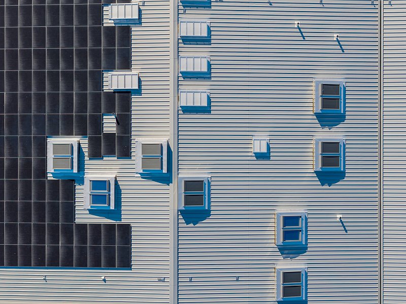 Senkrechte Luftaufnahme eines Metalldachs mit Dachfenstern und Solaranlagen.