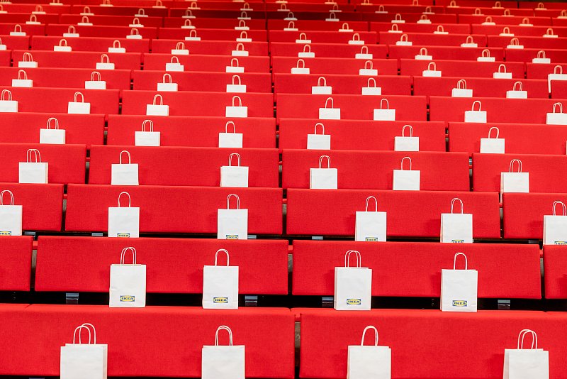Reihen roter Sitze mit bereitgelegten weissen Taschen vor Beginn einer Konferenz.